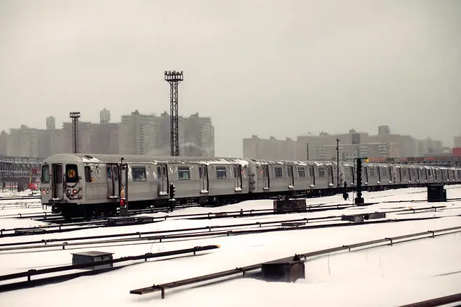 snow falls on outdoor subway tracks